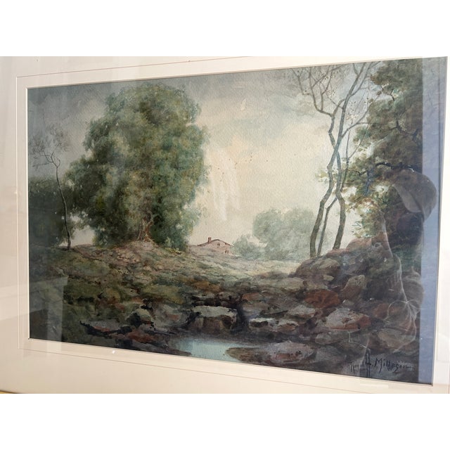 This beautiful gold framed, watercolor depicts a serene landscape with a small house, trees, and a stream. Signed by Royal...