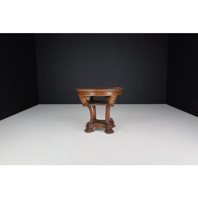Italian Neoclassical Round Walnut Center Table with Carved Figural Legs, Italy, 1920s A refined Italian neoclassical-style...