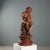 Patinated terracotta sculpture depicting a boy with a dove sitting on a stump. The statue is presented on a circular stand...