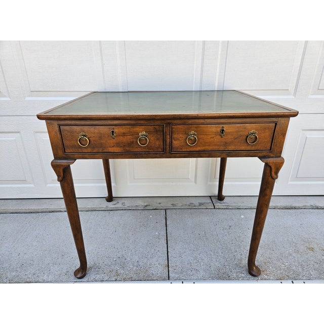 A gorgeous George III style writing desk with a tooled green leather top. This writing desk is made by Baker Furniture and...