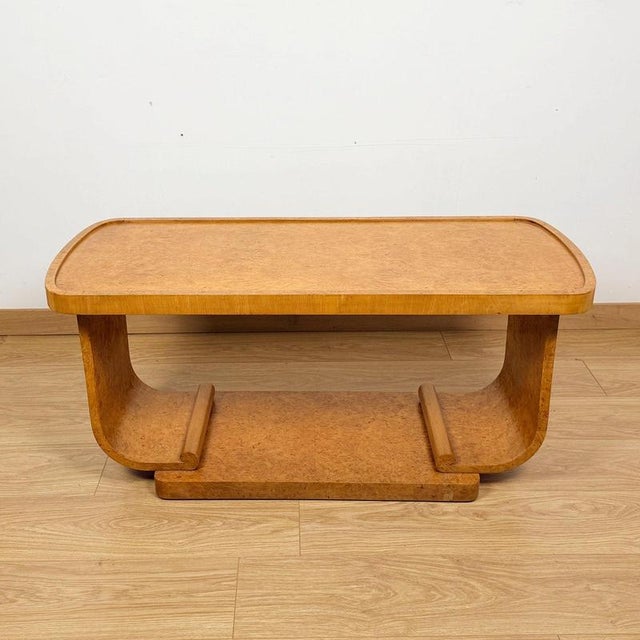 An Art Deco coffee table by with U-Shape base by Harry & Lou Epstein Burr walnut veneered throughout. Dimensions: H 49cm W...