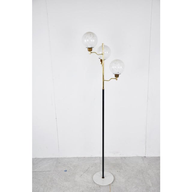 Mid-Century Modern brass and balck metal floor lamp with three murano glass globes. Beautiful round marble base. This lamp...