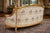 A romantic 1980 French Louis XVI–style settee, handcrafted from solid beechwood and finished in an elegant antique gold...