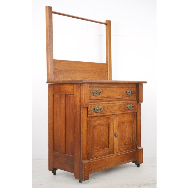 Antique Victorian style washstand made of quarter sawn oak with casters. It features a tall back rail designed to hold a...