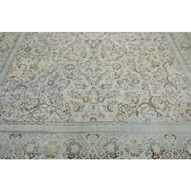 This hand-knotted mahal wool rug features a beige color field accented by blue and brown hues arranged in a classic floral...