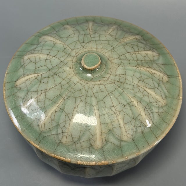This Chinese Longquan celadon lidded bowl features carved lotus petal patterns on both the bowl body and lid. The glaze...