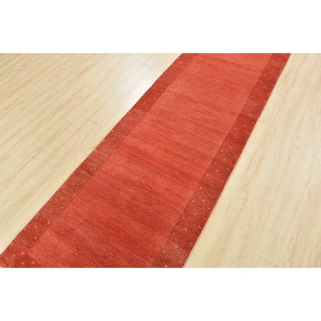 This contemporary Gabbeh runner is hand-knotted with an all-wool pile on a cotton foundation. This rug is new and in...