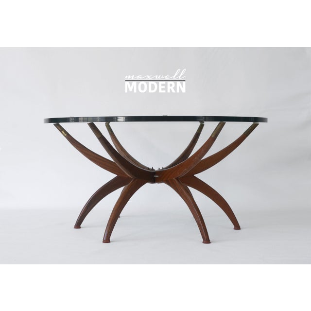 Stunning mid century coffee table with folding wooden spider legs and a 36" diameter round glass top. Legs have brass...