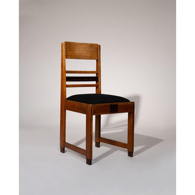 A set of four Amsterdam School dining chairs, Netherlands, 1920s. Crafted in solid oak with subtle coromandel details,...