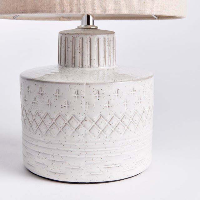 A ceramic base, this little lamp has a speckled, reactive glaze that plays off the carved graphic pattern. Topped with a...