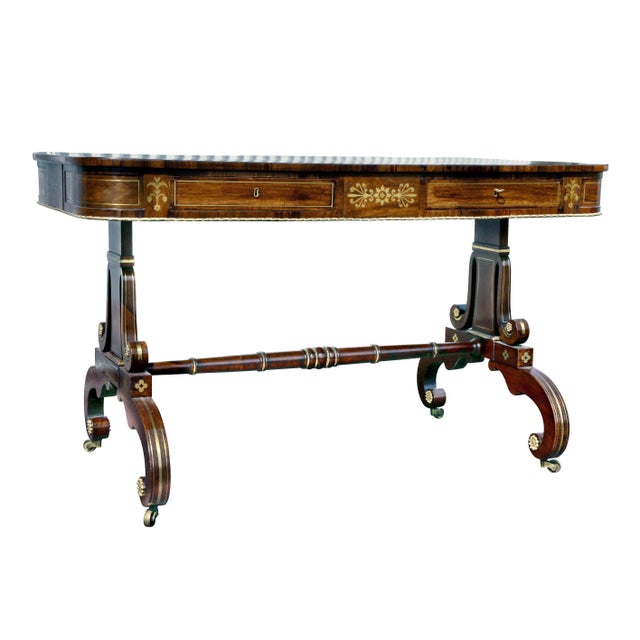 With a rectangular green inset leather top with crossbanded brass inlaid edge over two drawers with brass inlays all...