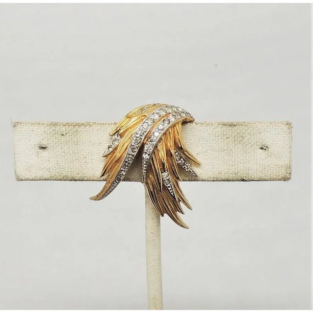 This is part of Chairish’s Costume Jewelry assortment. 1950s goldtone and clear rhinestone small fur clip. Marked "Jomaz."...