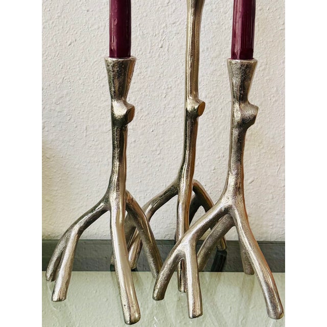 A striking trio of sculptural candlesticks in a naturalistic branch form, finished in a silver-toned metal. The organic...