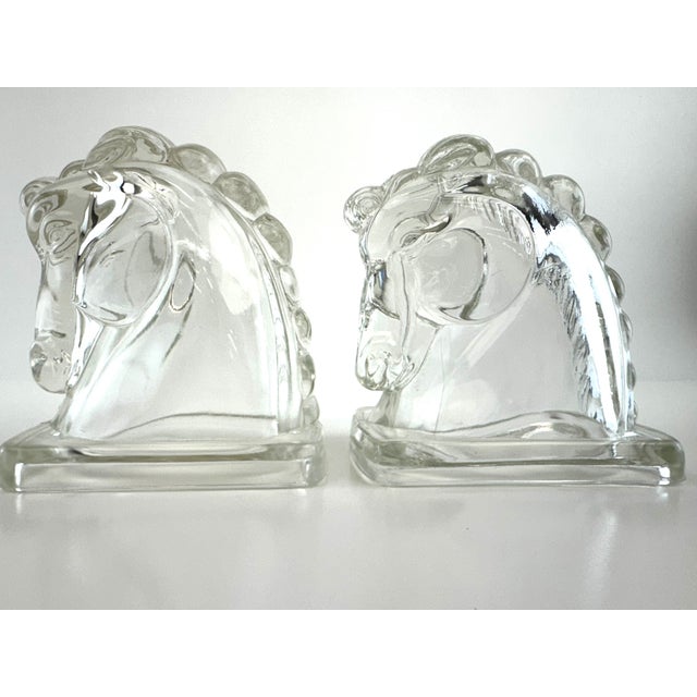Striking pair of French Art Deco molded glass bookends depicting stylized horse heads. Crafted in heavy clear pressed...
