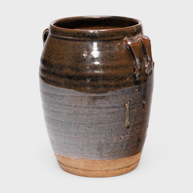 This antique Chinese jar from the early 20th century is cloaked inside and out with a glassy brown glaze that sheets down...