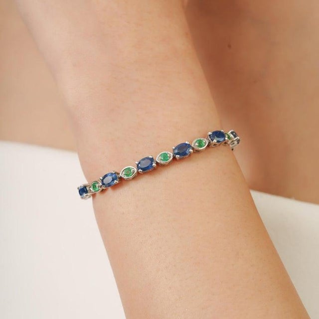 Crafted in 925 sterling silver, this elegant tennis bracelet features natural blue sapphires and emeralds beautifully...