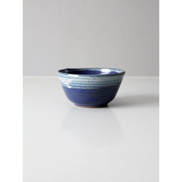 A vintage studio pottery bowl, signed by the artist. The hand-crafted form features a rich blue glaze with a softly...