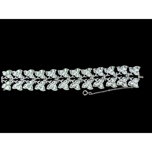 Offering a 1950-60’s vintage bracelet with a repeating leaf design by Coro. It has a fold-over clasp, safety chain, and a...