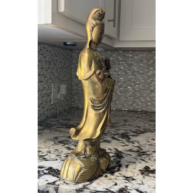 Vintage cast brass Guanyin (Kwan Yin), the Bodhisattva of Compassion, standing atop a beautifully detailed fish and wave...