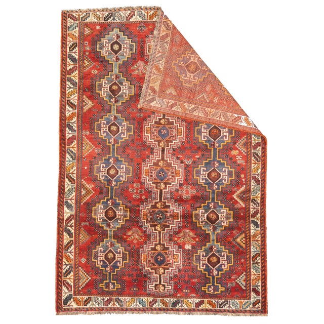 Fine vintage Persian Qashqai hand-knotted rug featuring repeating tribal geometric motifs across a vibrant red field. The...