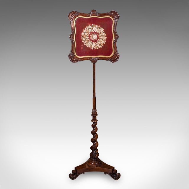 This is an antique pole screen. An English, rosewood and glass embroidered fireside heat reflector, dating to the William...