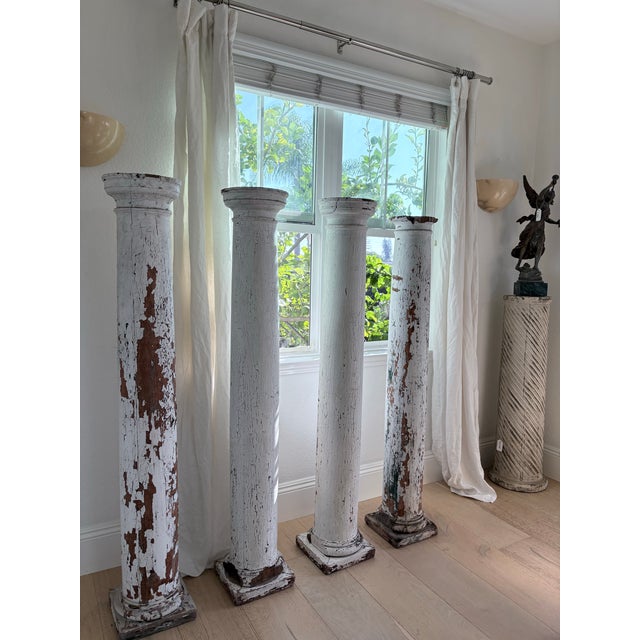 Striking set of four large solid wood architectural columns with beautifully aged white painted finish and authentic...