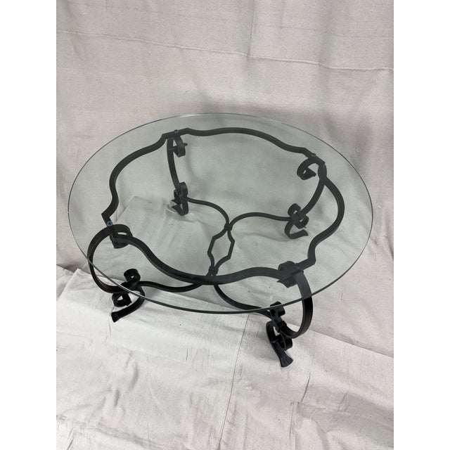 A sculptural French wrought iron table, hand-forged with elegant scrolls and crisp hammer detailing throughout the base....
