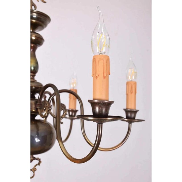 Beautiful six-armed flemish chandelier made of patinated brass. The arms are decorated with faces. The chandelier has a...