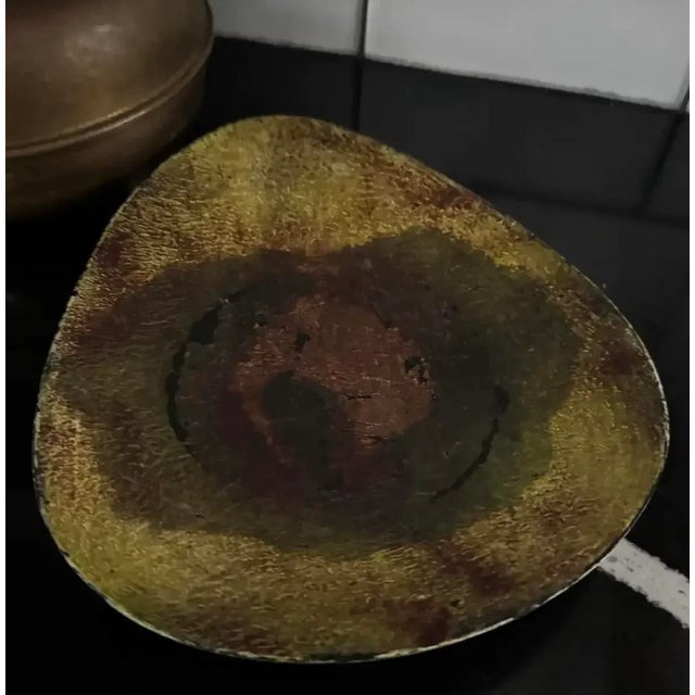 A sculptural mid-century Italian brass dish with a freeform organic silhouette and rich natural patina in layered tones of...