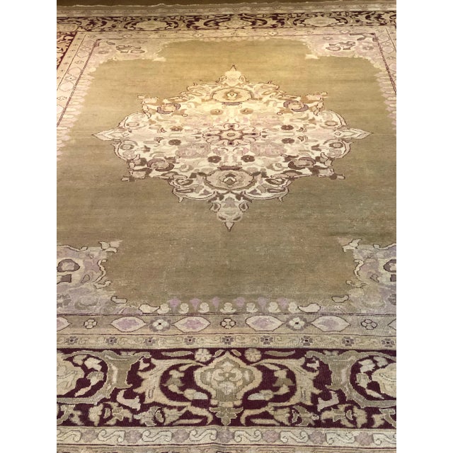 Indian production carpet with pastel tones. A large beige medallion rests in the green lemon-coloured field. The rich...