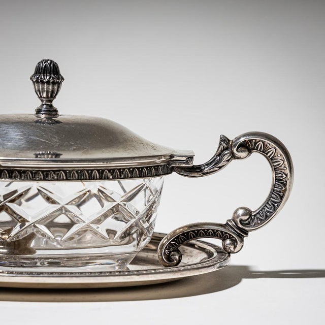 Oval lidded box with faceted glass insert, resting on four lion paw feet and set on a matching tray. The lid features a...