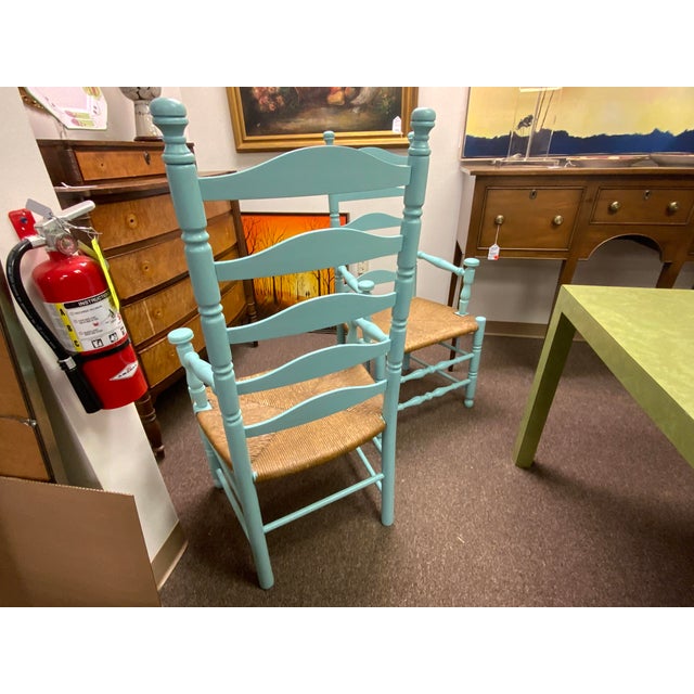 20th century pair of ladder back arm chairs. Mushroom cap arm holds and top detail. Rush seats. These chairs have been...
