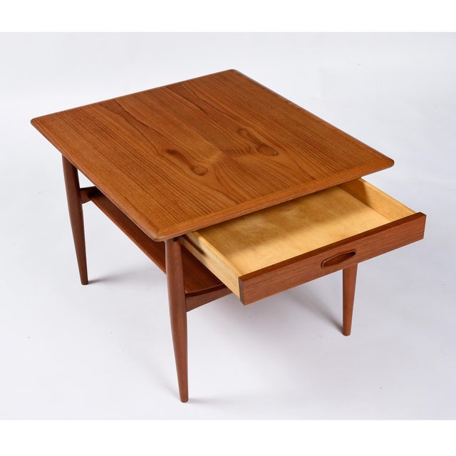 A well-proportioned pair of Danish lamp tables in solid teak, each raised on gently tapered, round turned legs with a...