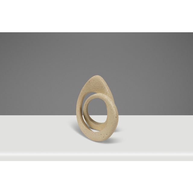 Introducing an alluring textured sculpture of two intertwined loops that showcase a fluid, interlocking design that...