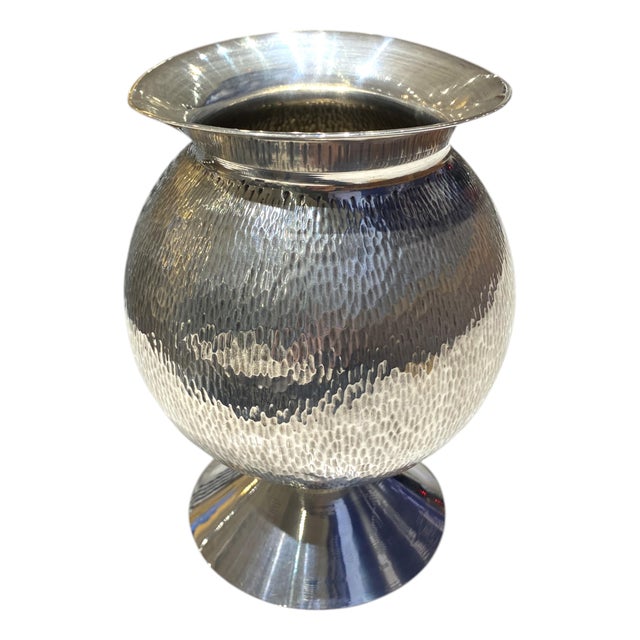 A stunning sculptural silver plate vase featuring a rounded, hand-hammered body and elegant organic flared rim. The richly...