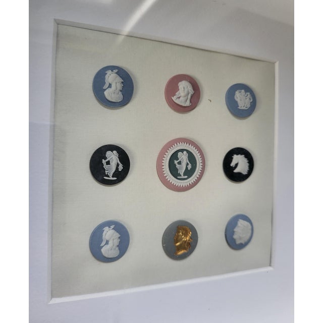 This elegant framed piece features a curated collection of nine authentic 20th-century Wedgwood Jasperware unglazed...