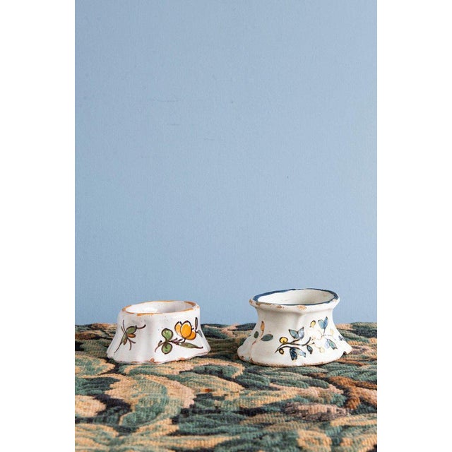 This pair of 18th-century French faience salt pigs from Rouen is decorated with joyful flowers and insects in orange and...