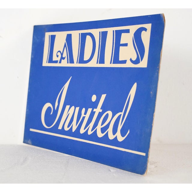Vintage retail cardboard wall sign with a blue background and white lettering. The sign reads, Ladies Invited". Good...