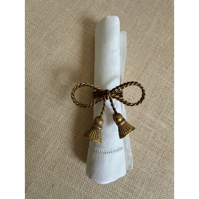 Set of 13, vintage, mid century Regency, brass Napkin Rings crafted to look like a bow-tied chord with hanging tassels....