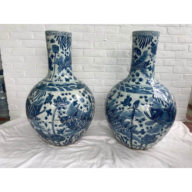 Very large pair of Chinese blue and white vases depicting fish... one with cracked base and repair work.... the other in...