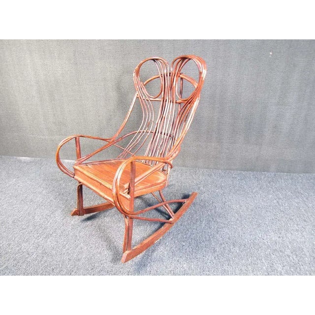 This incredibly unique rocking chair is made from intricately woven and fastened tree branches. it has a flat wood seat...