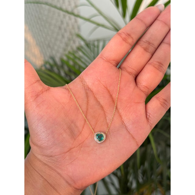 This Pendant necklace features a 0.8 carat heart-shaped natural emerald set in 14K yellow gold. The emerald measuring...