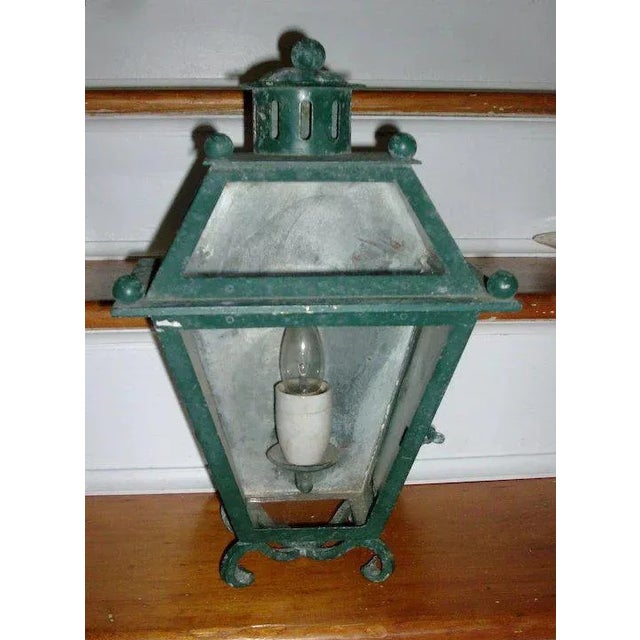 An exceptional iron wall sconce with original green paint in the form of a half lantern containing a single candle light....