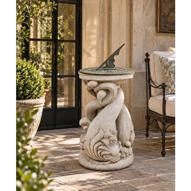A striking vintage neoclassical garden pedestal featuring three intertwined dolphins supporting a shallow circular basin....