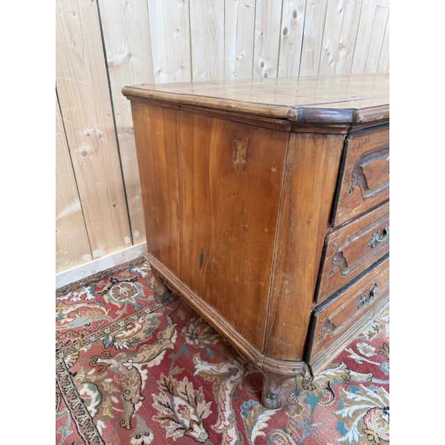 A louis xv period commode, crafted from solid cherry wood, featuring three wide drawers with shaped fronts. the fronts are...