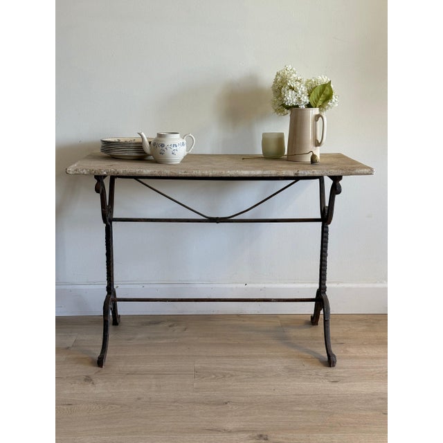 Rectangular marble top in soft cream and pink veining, propped on a cast iron base of scrolled supports joined by a turned...