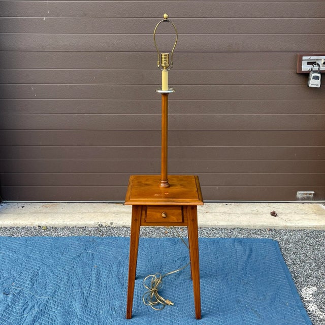 A late 20th century Ethan Allen Country Craftsman collection Traditional Rustic pine floor lamp having a small pine table...