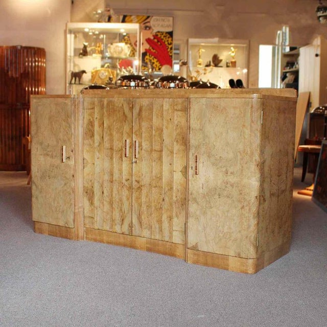 An Art Deco Sideboard by Harry & Lou Epstein. beveled burr walnut central doors with drinks cabinet and three integral...