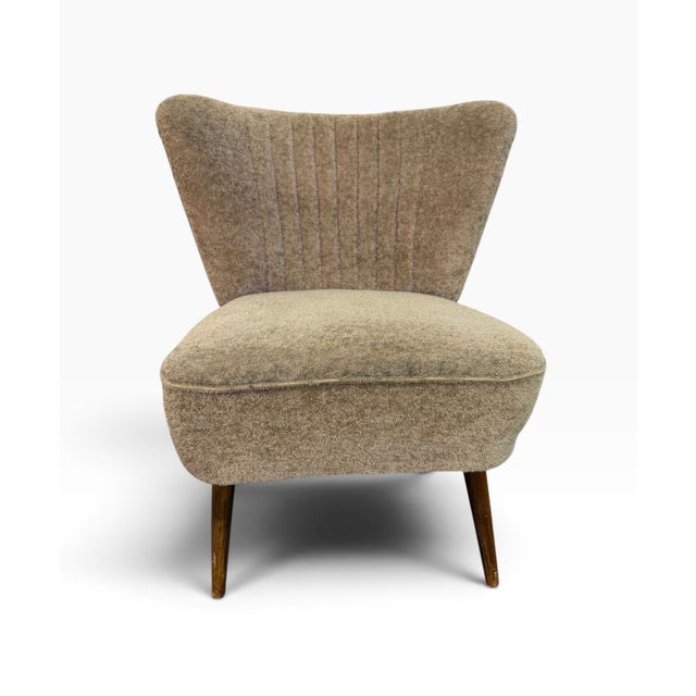 Mid-Century Modern upholstered slipper chair dating to the 1960s, featuring a distinctive sculptural silhouette and...