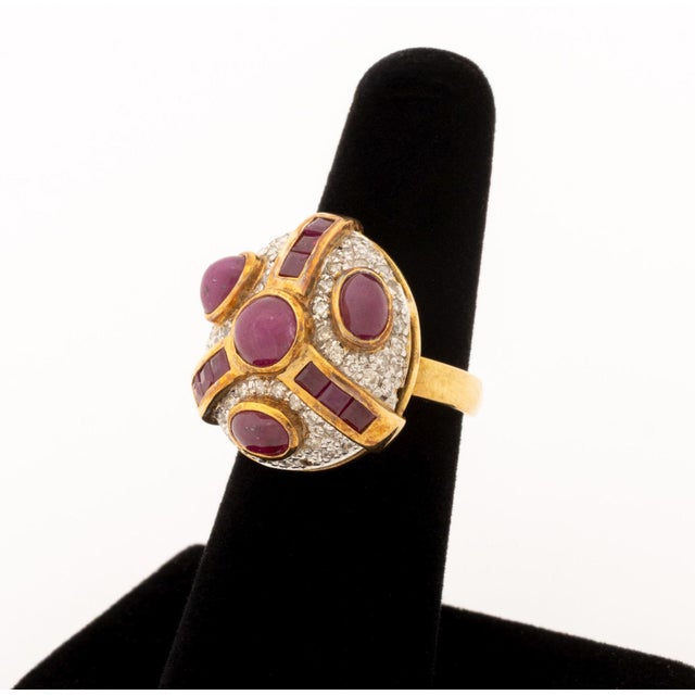 18K Yellow Gold, Ruby, and Diamond Ring, featuring one bezel set round ruby cabochon, adorned further by three bezel set...